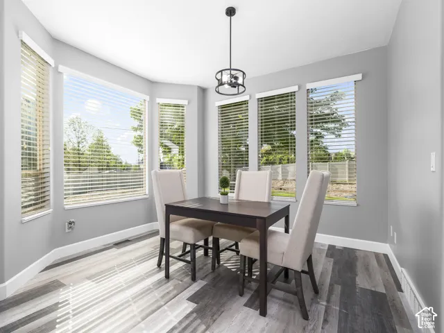 Dining area featuring a bay window with multiple windows, wood-finish flooring, and a contemporary ceiling light fixture