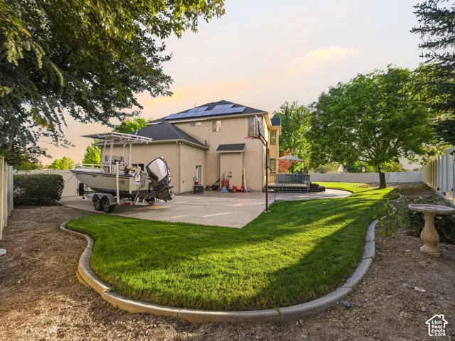 Expansive backyard featuring a large concrete patio, manicured lawn, and mature trees