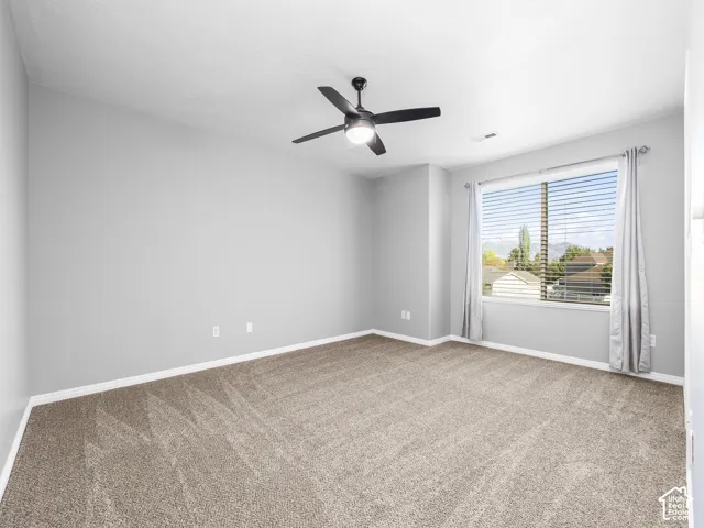 Spacious room featuring neutral carpeting, a large window with blinds, and light-colored walls