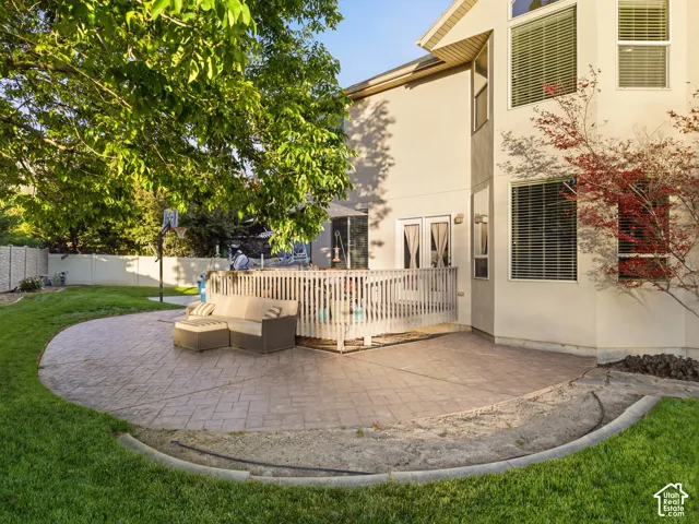 Expansive backyard featuring a large stamped concrete patio, a multi-level wooden deck, and a manicured lawn