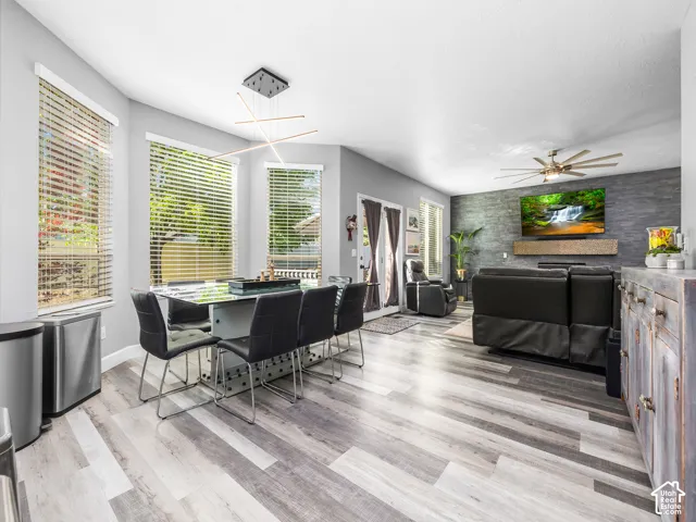 Open-concept living area featuring light gray wood-finish flooring, a modern linear chandelier, and ample natural light from multiple windows