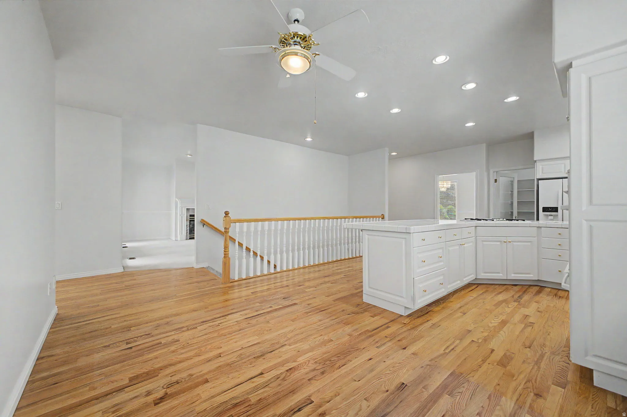 Kitchen and living area featuring wood-finish flooring, white cabinetry, a central island, and recessed lighting