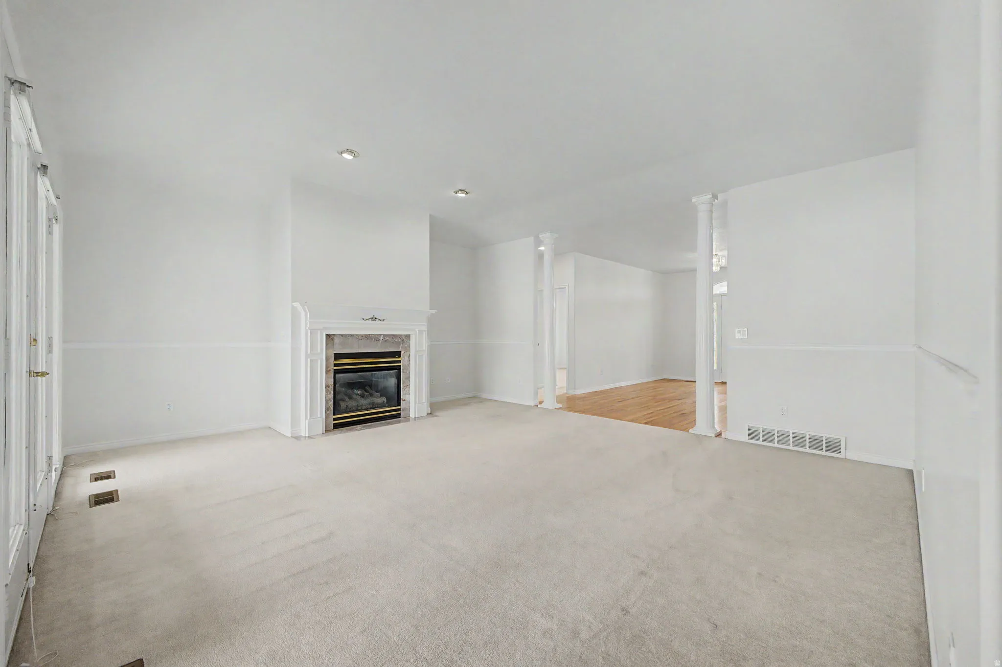 Carpeted room featuring a fireplace with a decorative white mantel, a stone surround, and a glass-front insert