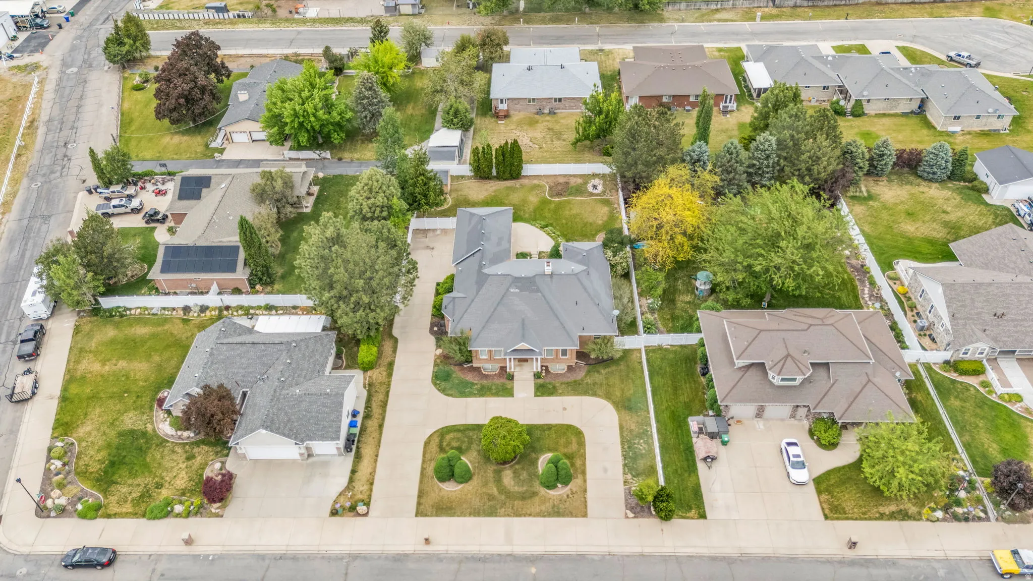 Expansive suburban property featuring a central residence with a paved circular driveway, mature landscaping, and a manicured lawn