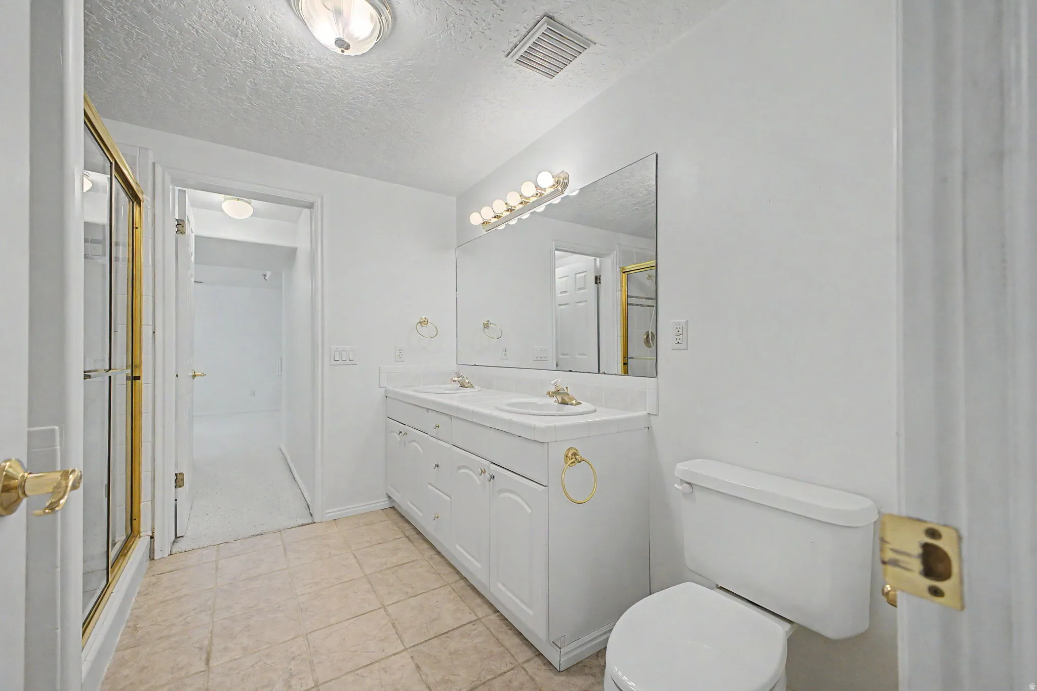 Bathroom featuring a double vanity with white cabinetry, dual sinks, and a large wall-mounted mirror