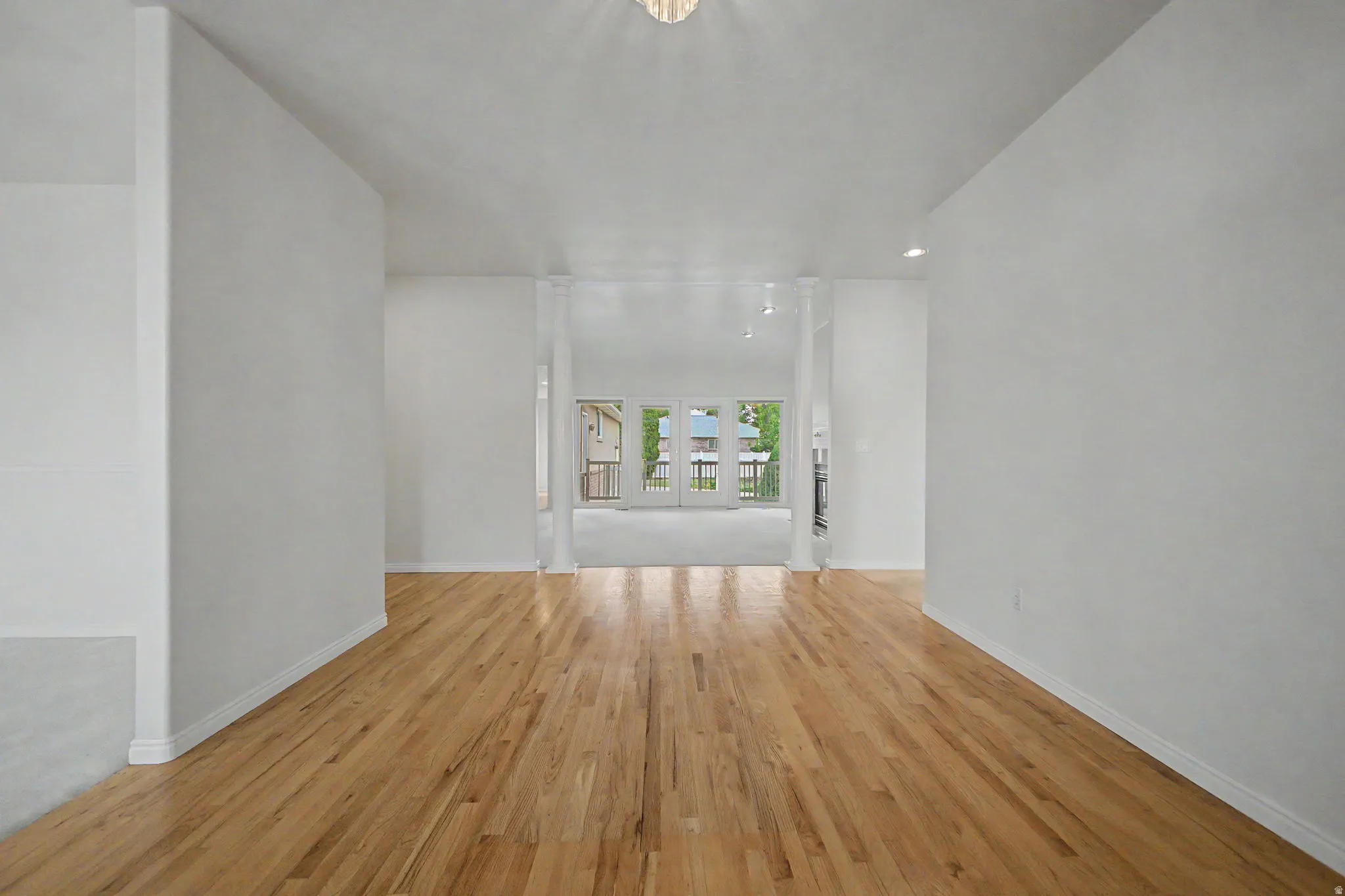 Light wood-finish flooring extending through an open interior with white walls