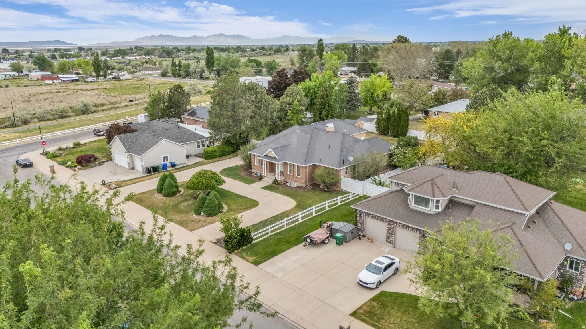 Aerial perspective showcasing multiple properties with mature trees and a distant mountain range