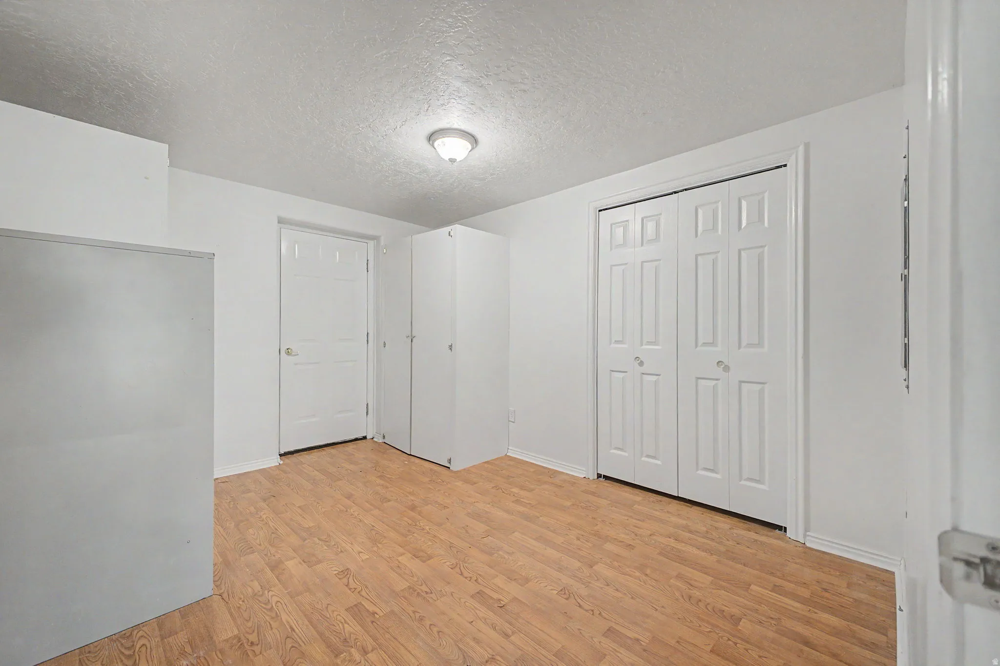 Room featuring wood-finish flooring, a bi-fold closet, and recessed lighting