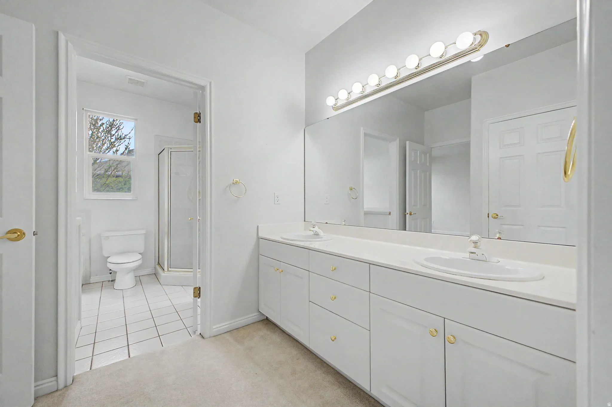 Double vanity with white cabinetry and gold-tone hardware