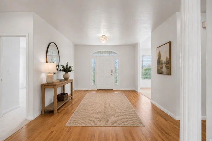 Virtually Staged-Bright entryway featuring wood-finish flooring, a decorative front door with arched transom, and a frosted glass chandelier