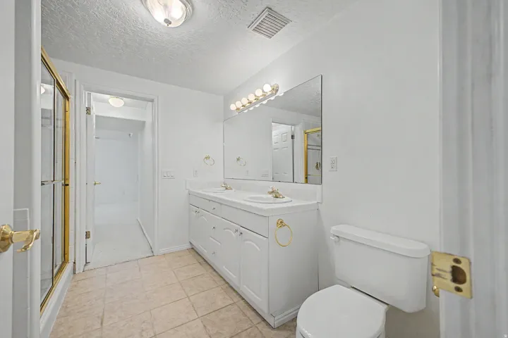 Bathroom featuring a double vanity with white cabinetry, dual sinks, and a large wall-mounted mirror