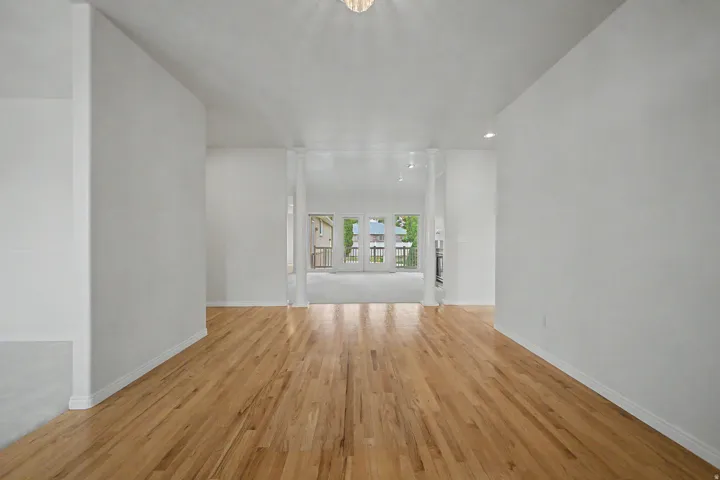 Light wood-finish flooring extending through an open interior with white walls