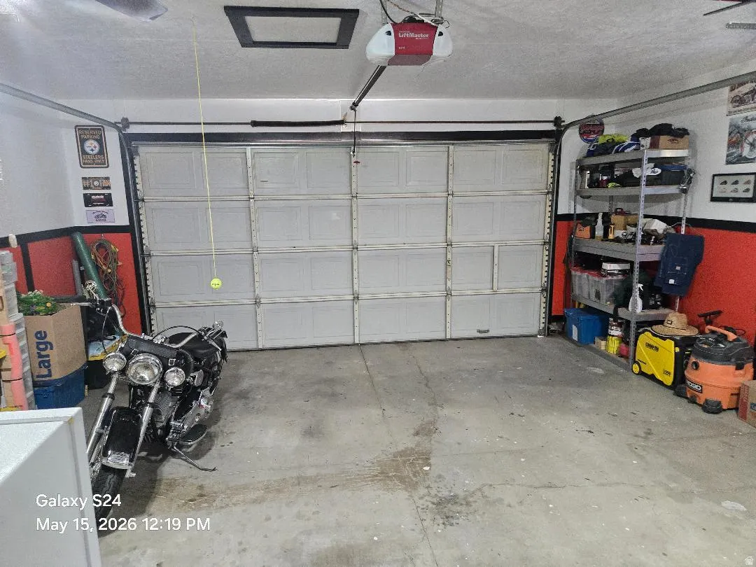 Attached garage featuring a panel garage door, concrete flooring, and ceiling-mounted garage door opener