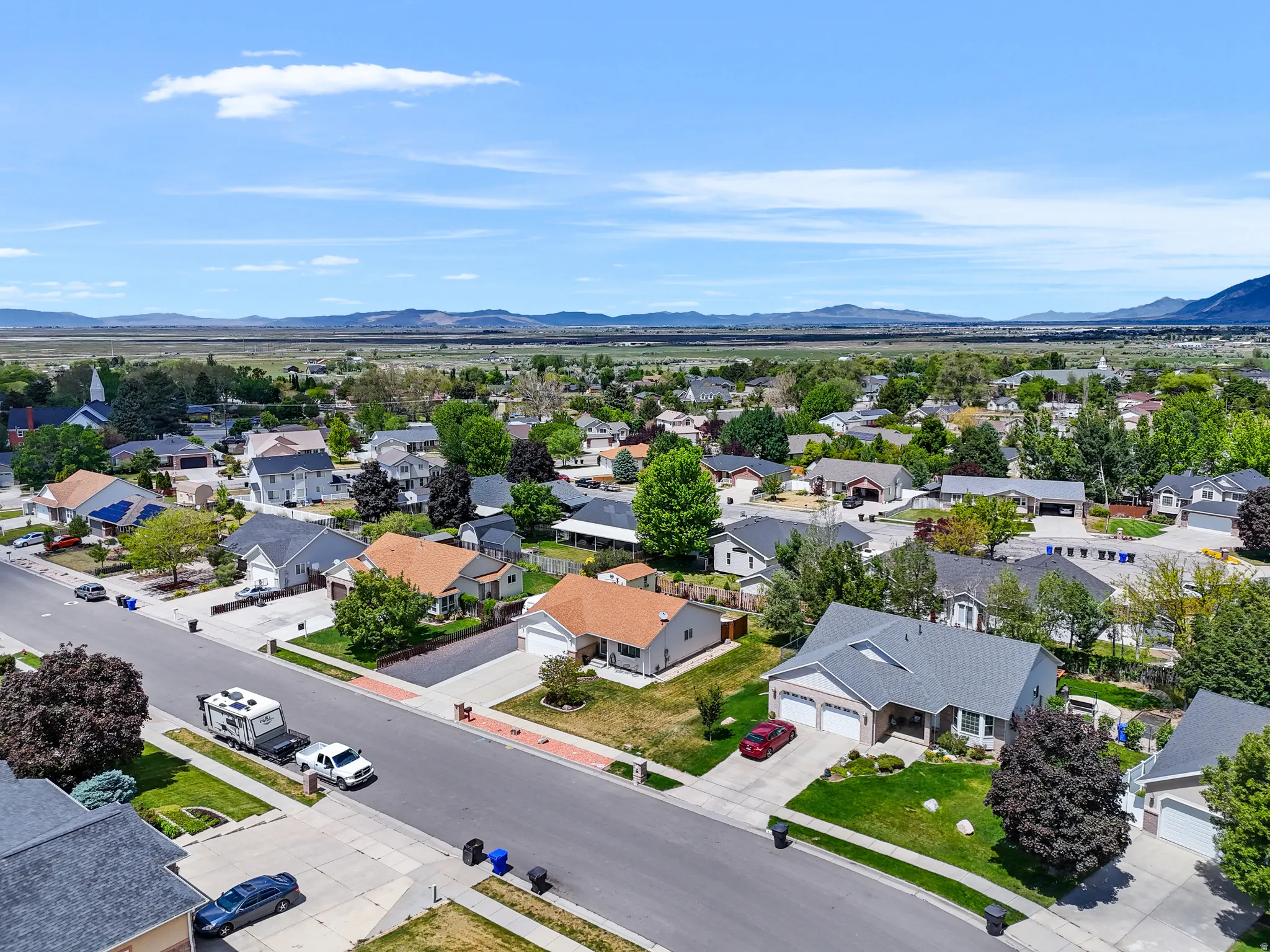 Suburban neighborhood featuring a variety of residential properties with mature landscaping and mountain scenery in the distance