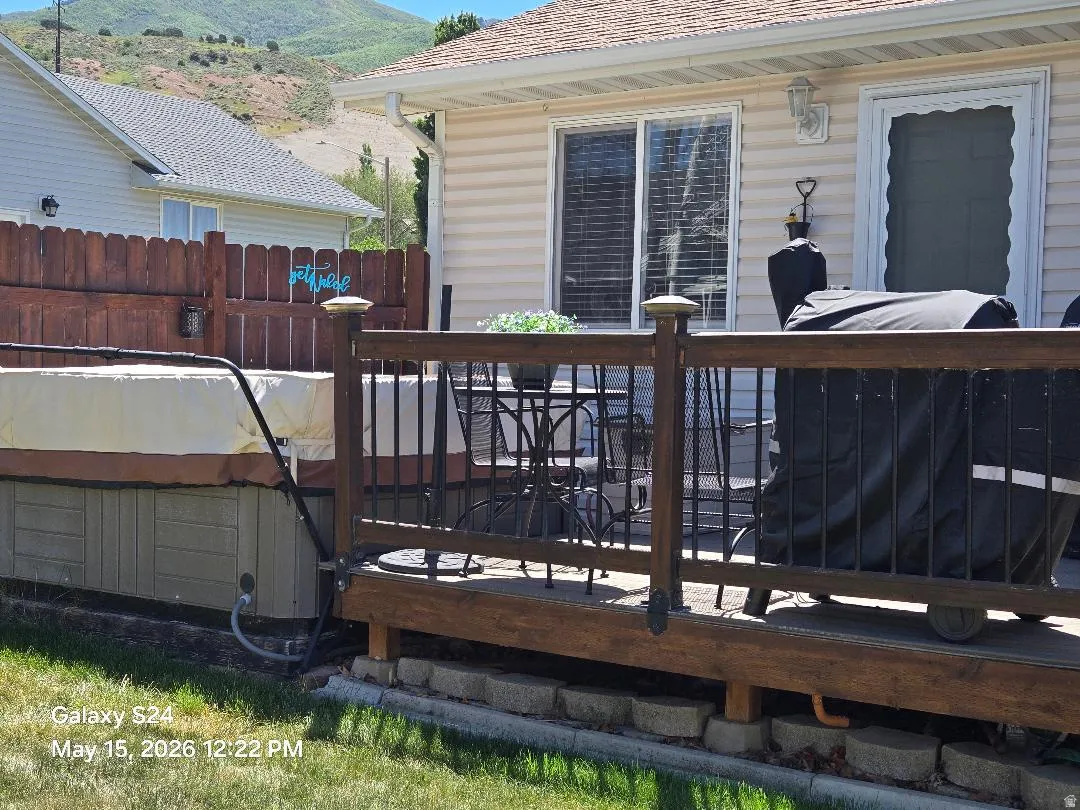 Expansive outdoor deck with wood railing and metal balusters and hot tub