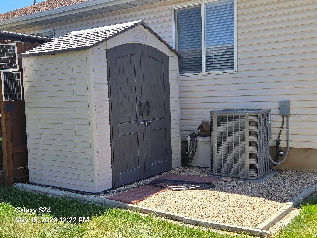 Storage shed with double doors, set on a gravel base with brick accents