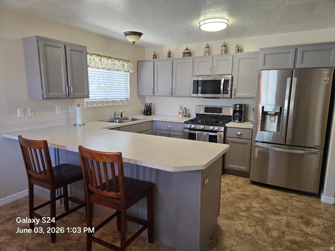 Kitchen featuring a peninsula breakfast bar, light-toned countertops, and gray cabinetry
