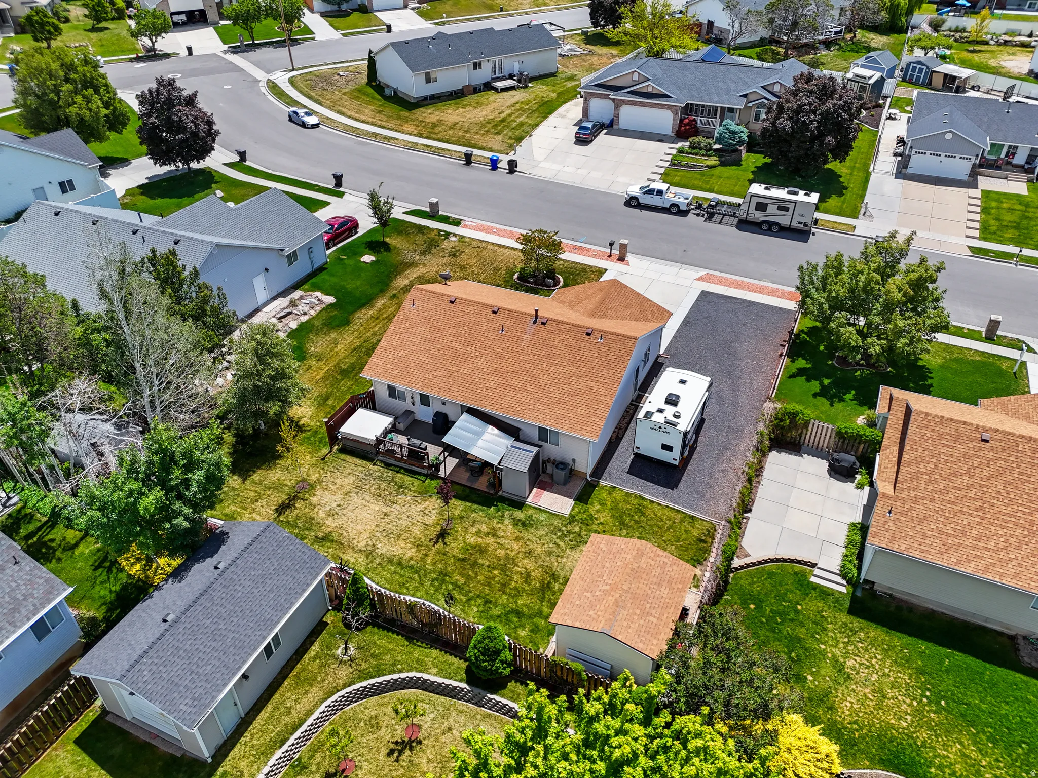 Rear exterior featuring a covered patio, a detached storage shed, a paved patio area, and a gravel driveway