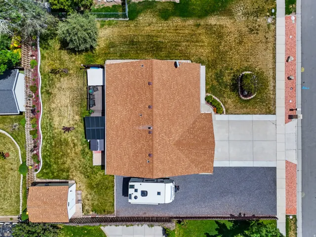 Property featuring a brown shingle roof, concrete driveway, and a gravel parking area