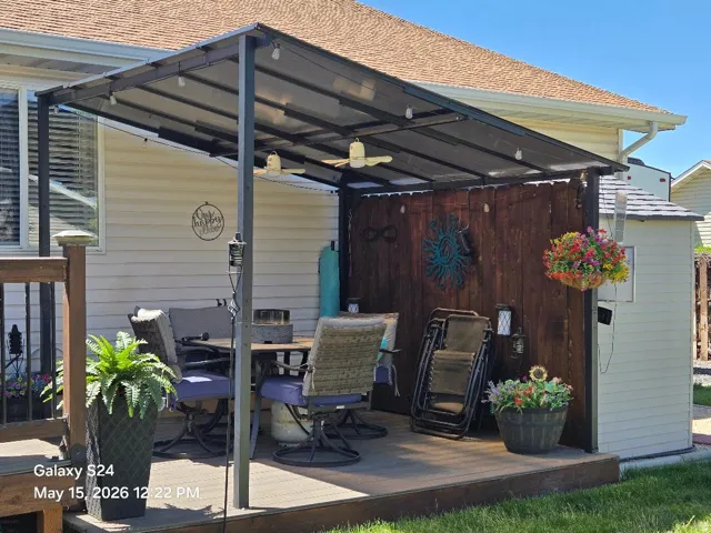 Spacious outdoor deck featuring a covered awning, string lighting, and ceiling fans