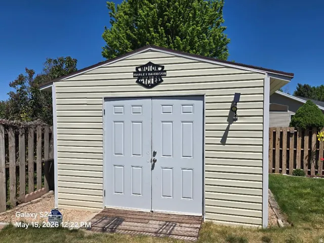 Detached storage shed/workshop featuring horizontal vinyl siding, a peaked roofline, and double white panel doors