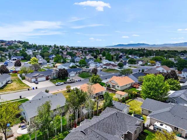 Expansive neighborhood setting with established homes, mature landscaping, paved streets, and mountainous terrain in the distance