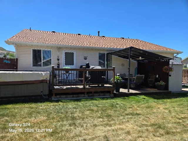 Expansive backyard featuring a manicured lawn, a multi-level deck, a covered patio area, and a storage shed