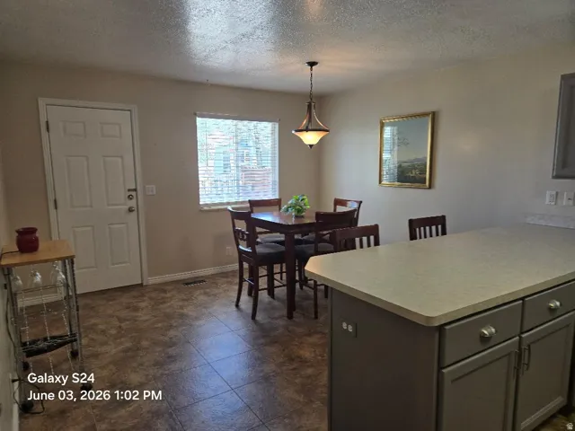 Dining area featuring a central window with blinds, a pendant light fixture, and tile flooring