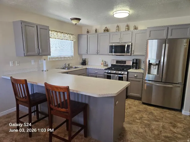 Kitchen featuring a peninsula breakfast bar, light-toned countertops, and gray cabinetry