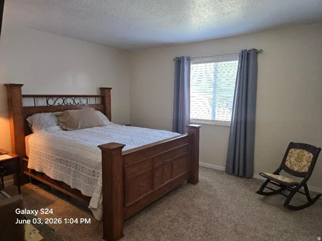 Carpeted room with a large window featuring blinds and grey curtains