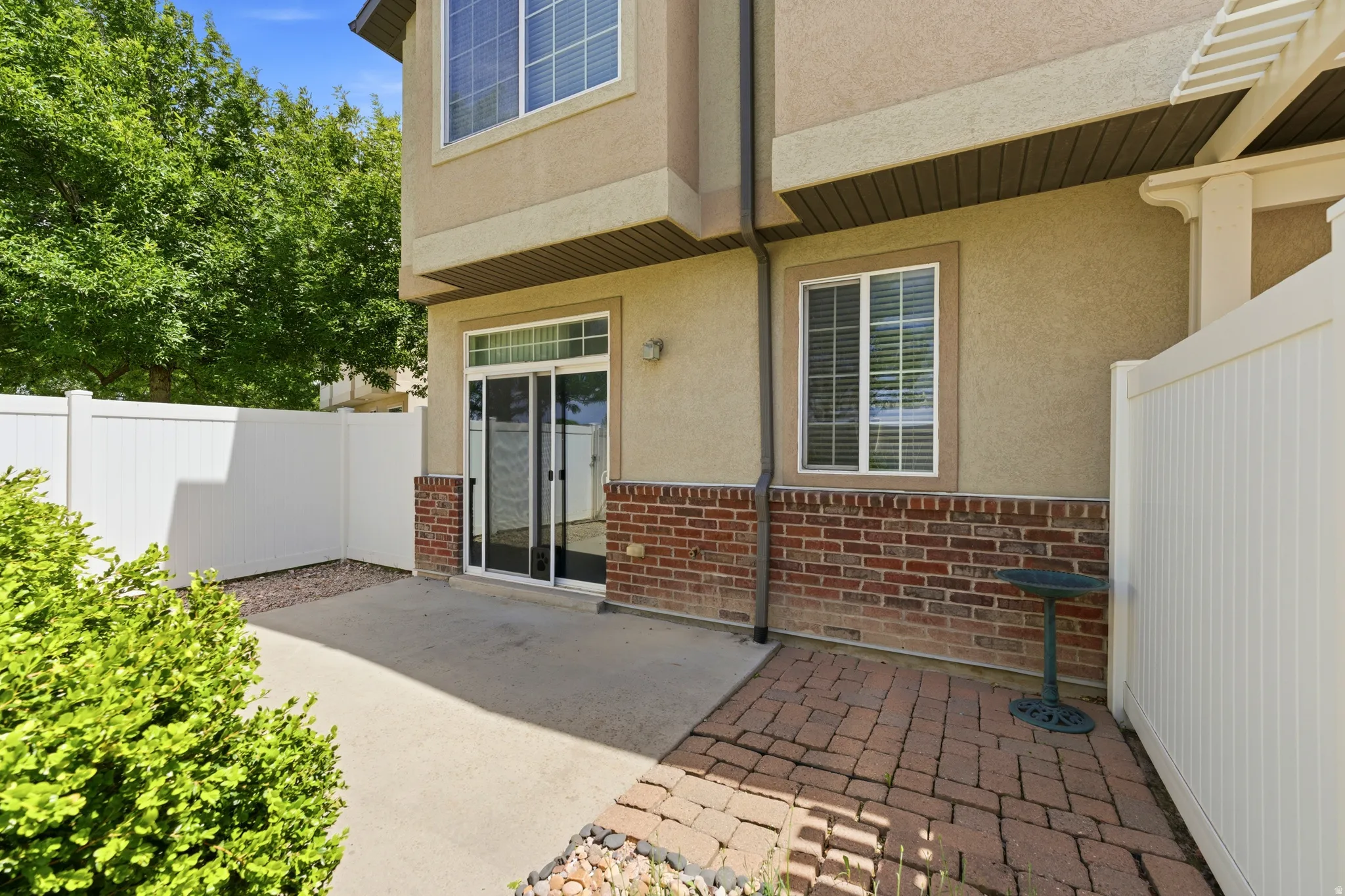 Private patio area featuring a concrete slab and a brick paver section