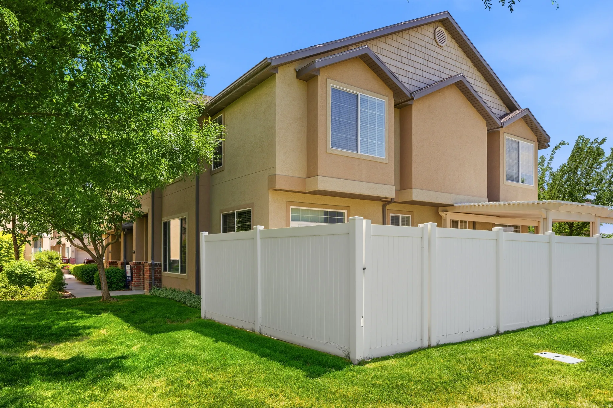 Cream stucco exterior with brown trim, featuring multiple windows