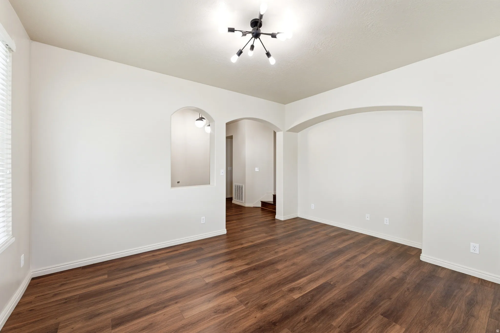 Spacious interior with rich wood-finish flooring, white baseboards, and neutral wall tones