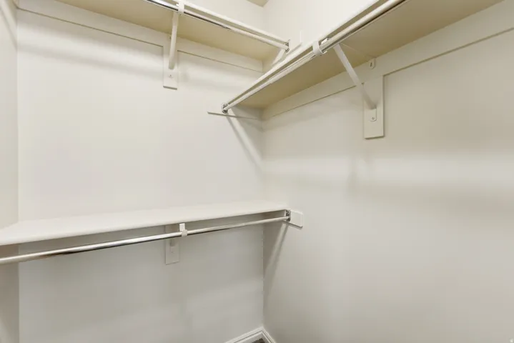 Spacious Primary closet with multiple shelving tiers and metal hanging rods