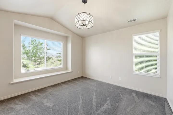 Spacious Primary bedroom featuring vaulted ceilings, a large window with an integrated window seat, and neutral wall tones