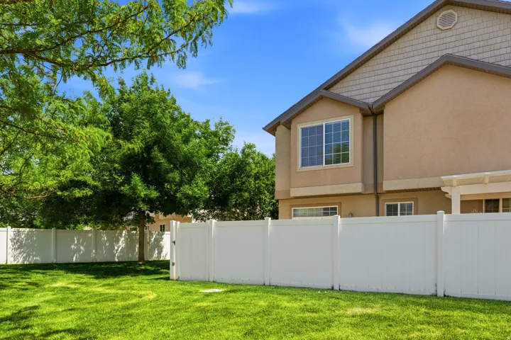 Expansive green lawn framed by a white privacy fence