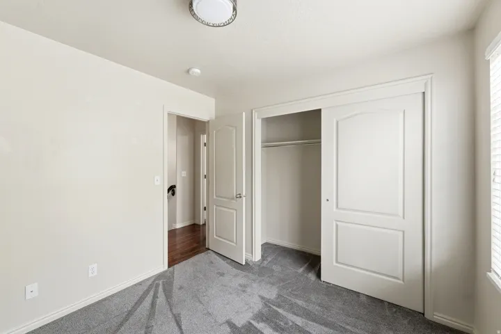 Guest bedRoom featuring gray carpet flooring, light-colored walls, and a built-in closet with sliding panel doors