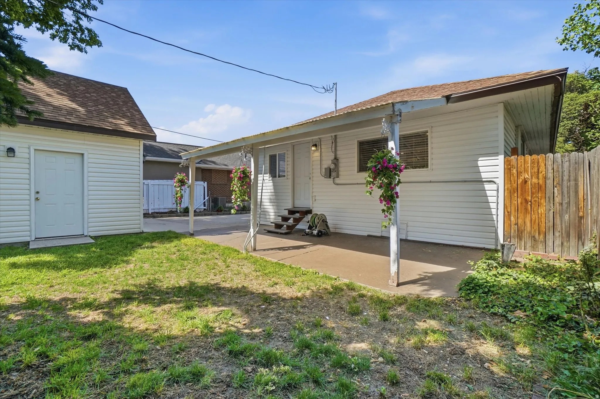 Backyard featuring a concrete patio with an overhead canopy, exterior siding, and a detached white-sided garage with a single door