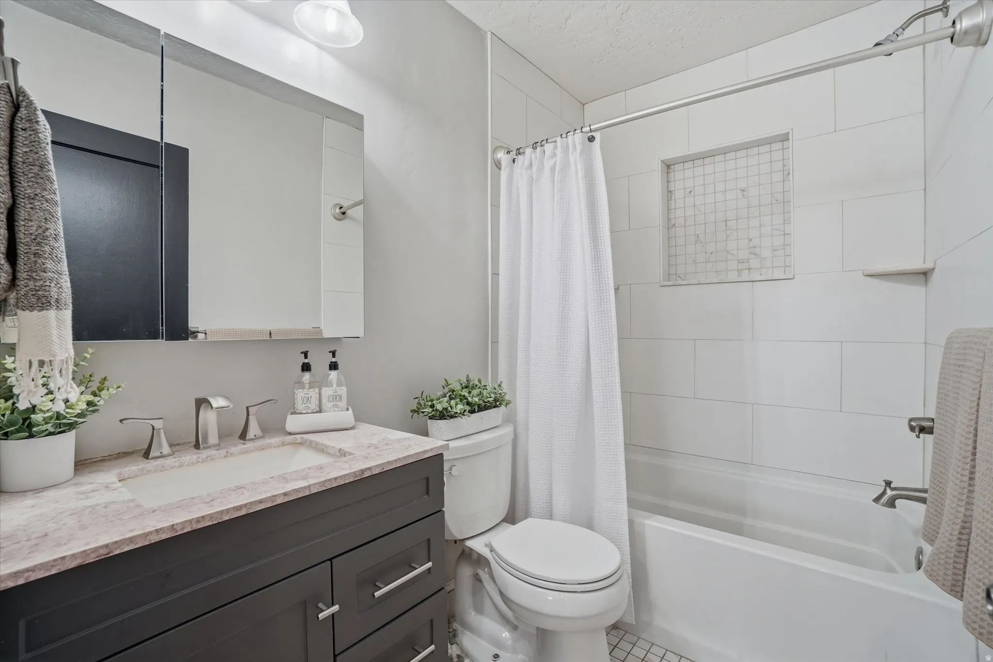 Contemporary bathroom featuring a dark wood-finish vanity with a built-in sink and brushed nickel faucet, a spacious mirror, and a tiled shower-over-tub combination with an integrated niche