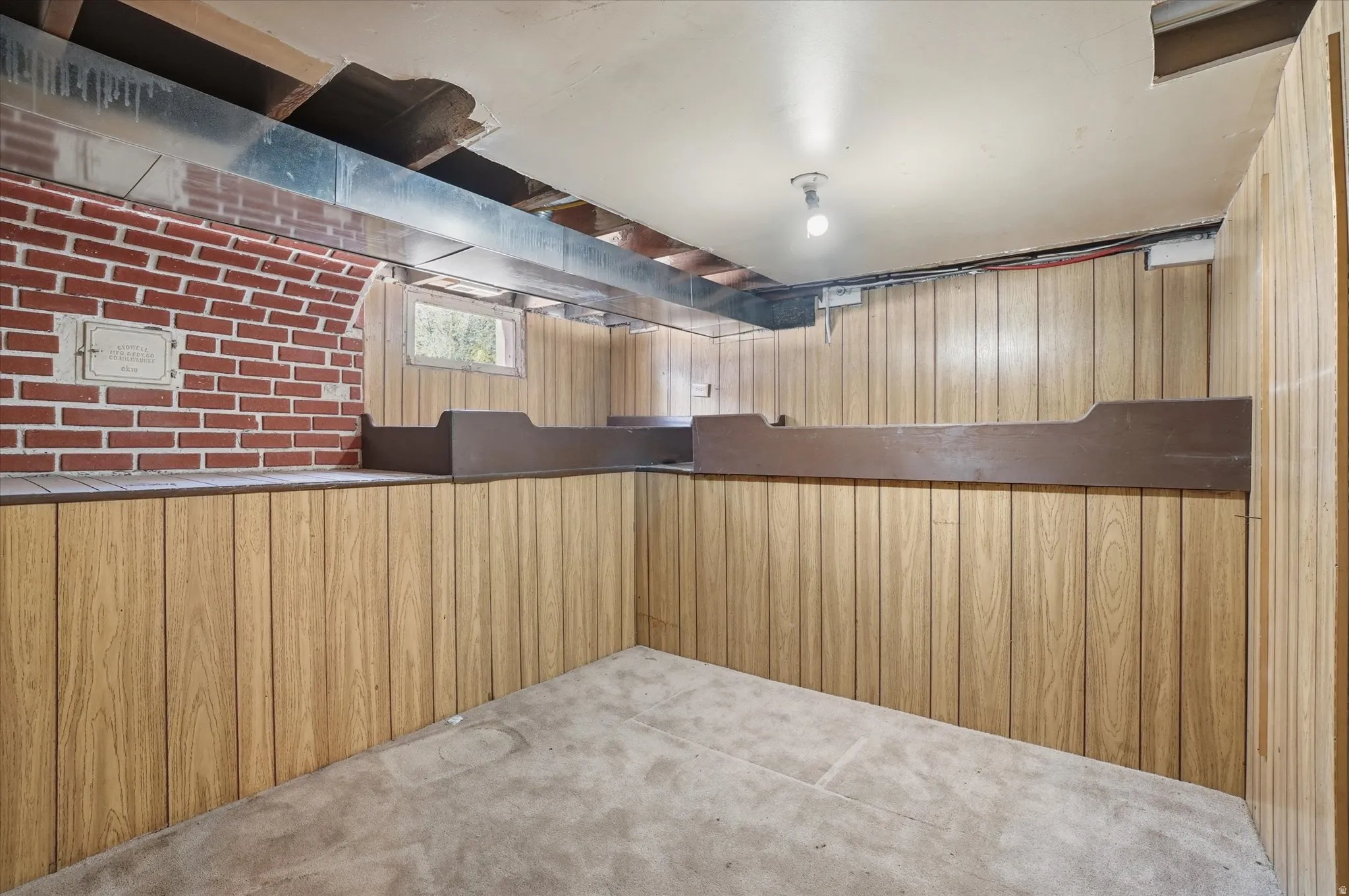 Lower level space featuring wood-finish paneling, exposed brick elements, and a concrete floor