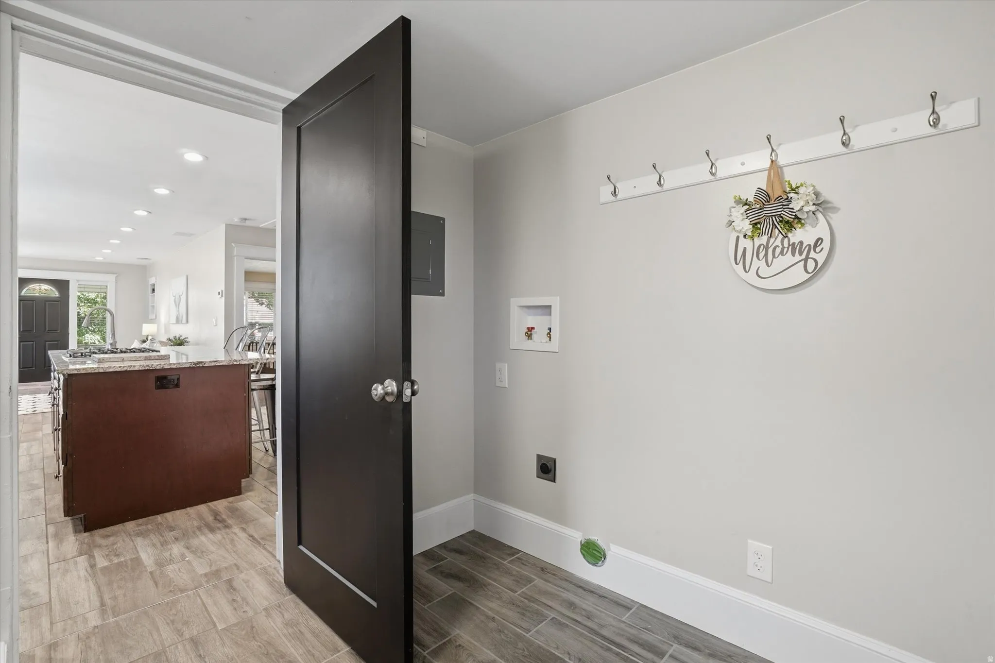 Dedicated laundry area with hookups for washer and dryer, featuring wood-finish flooring and a functional wall-mounted coat rack