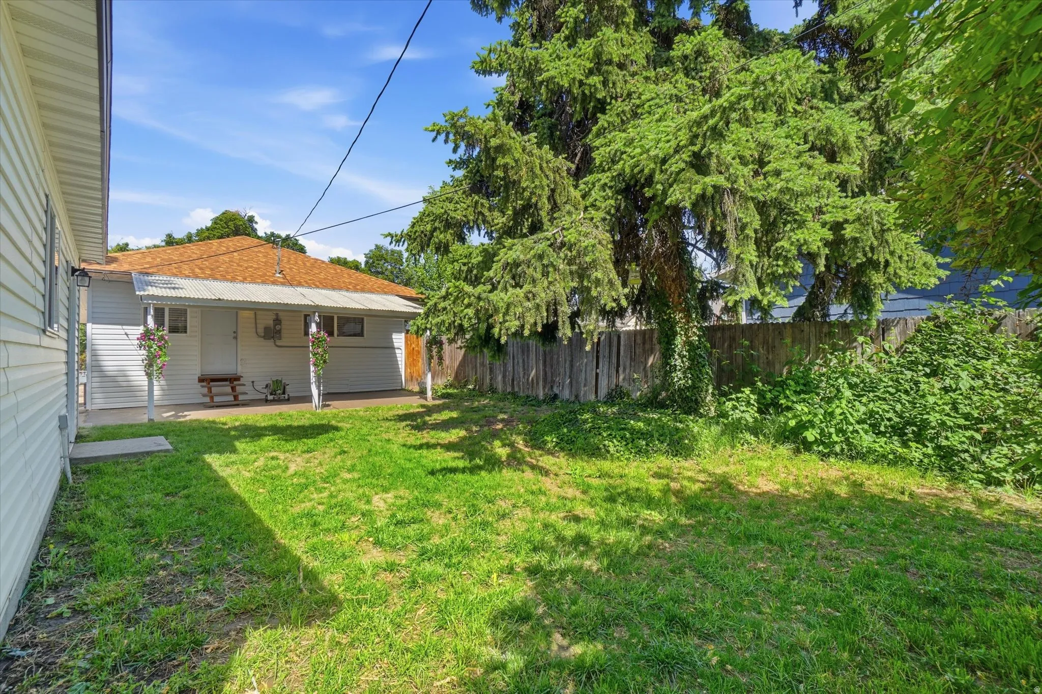 Expansive grassy area featuring a partial privacy fence and mature trees