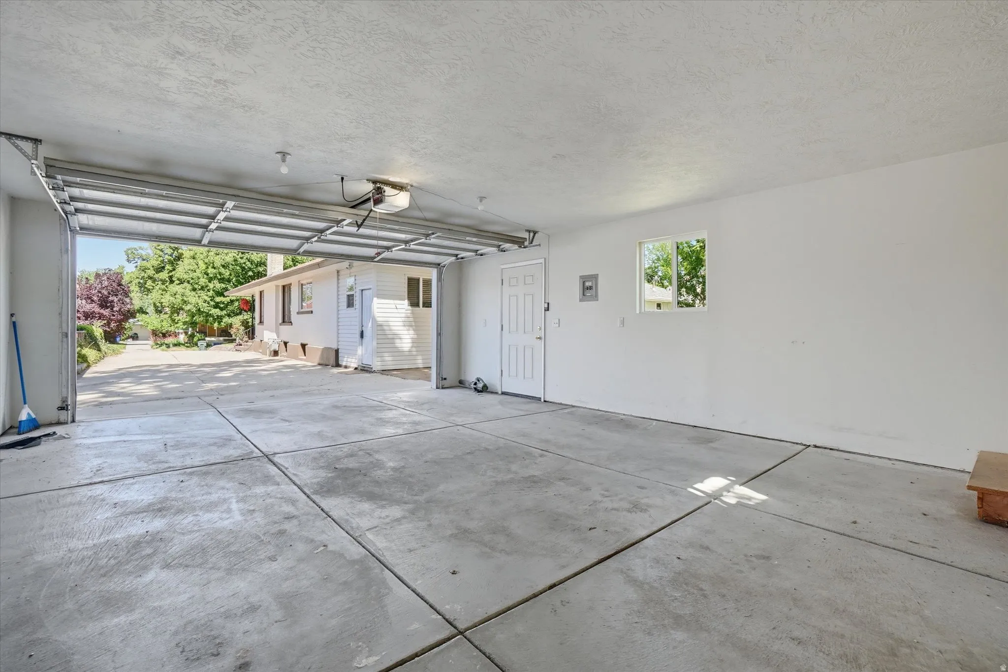 Spacious garage featuring a concrete floor, overhead lighting, and an automatic garage door opener