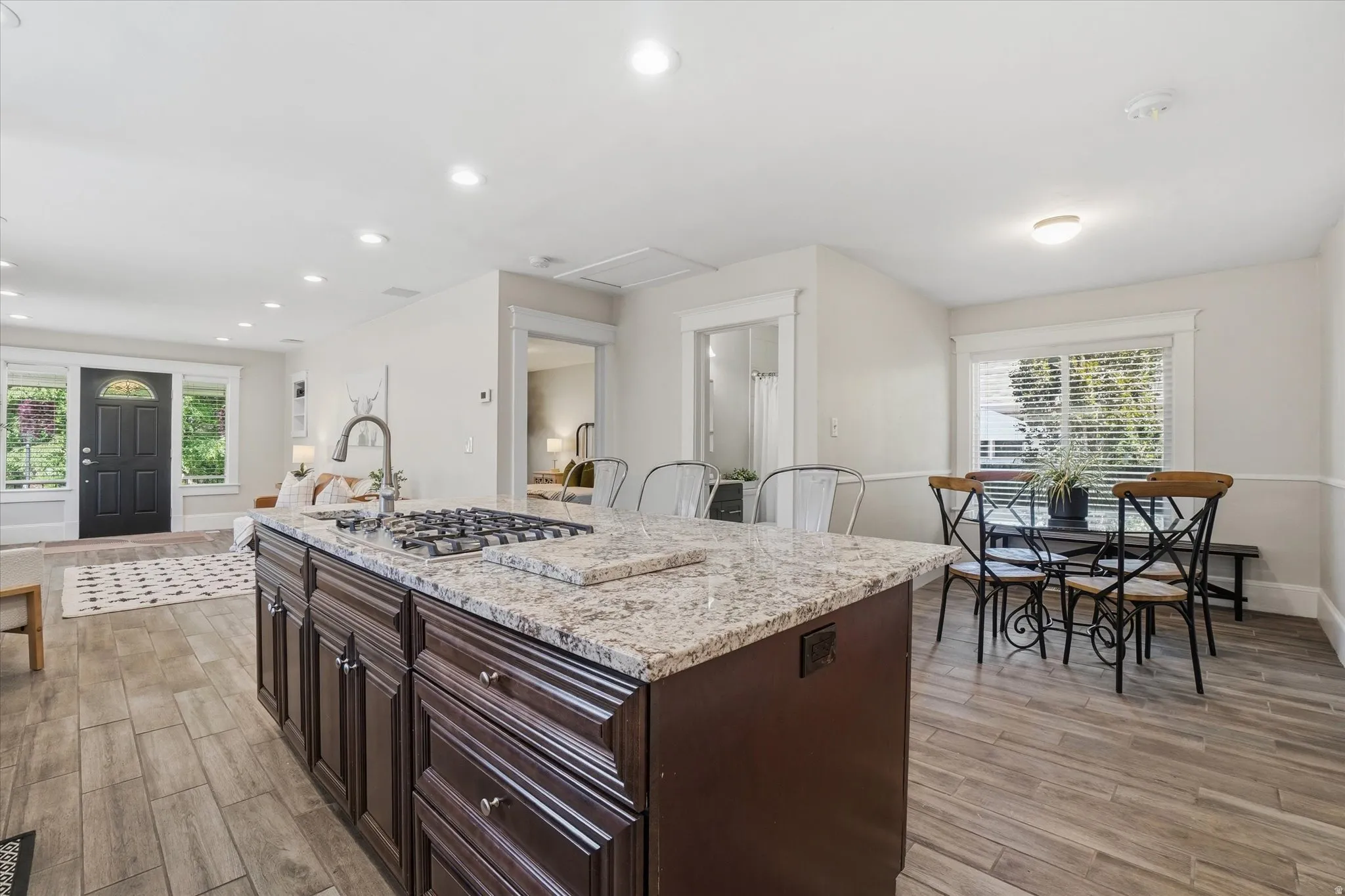 Kitchen island with a built-in gas cooktop, granite-style countertop, and dark wood cabinetry