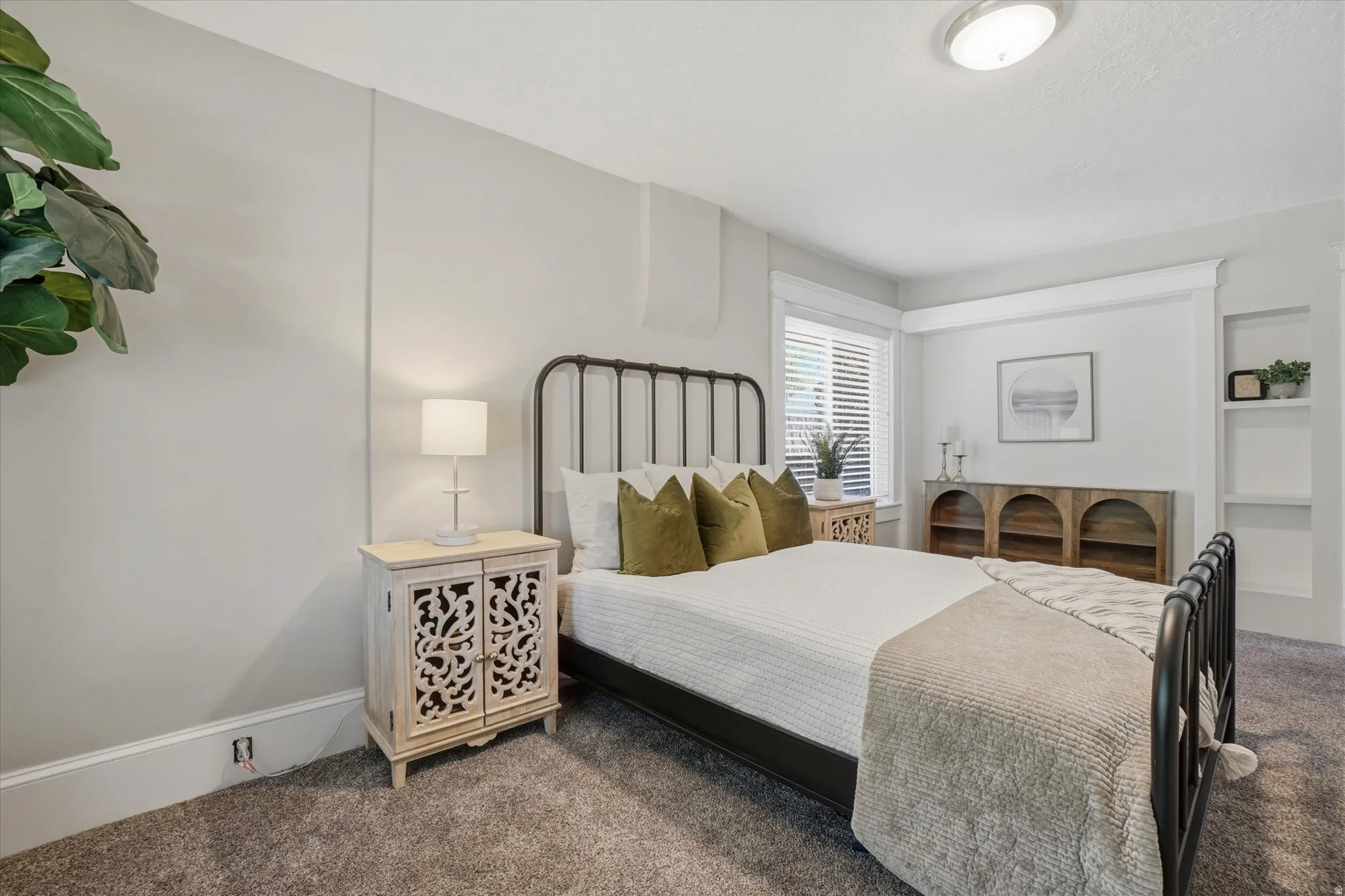Bedroom featuring textured carpeting, window with blinds, recessed built-in shelving, and flush-mount ceiling lighting