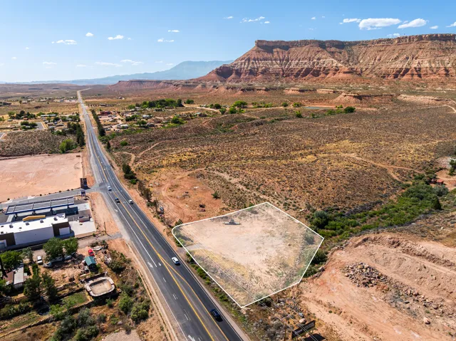 Expansive desert parcel featuring direct road frontage, prominent red rock mountain backdrop, and natural vegetation