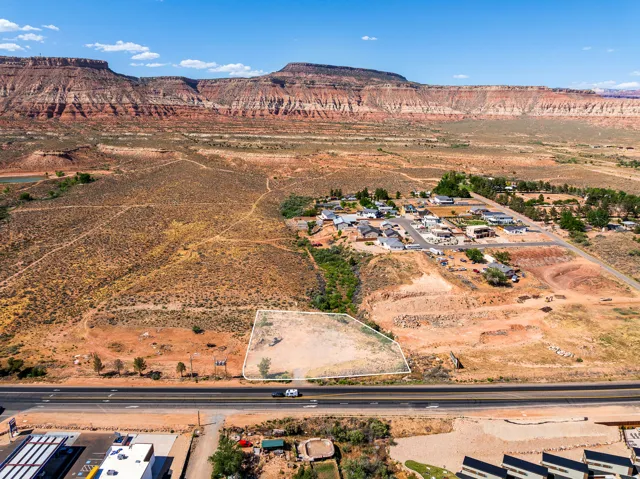 Expansive desert landscape featuring red rock formations and a prominent road frontage