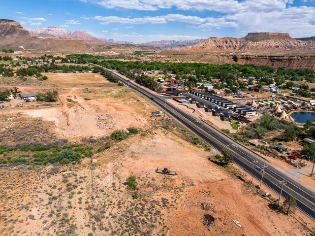 Expansive desert landscape featuring a paved roadway, scattered buildings, and distant mountains