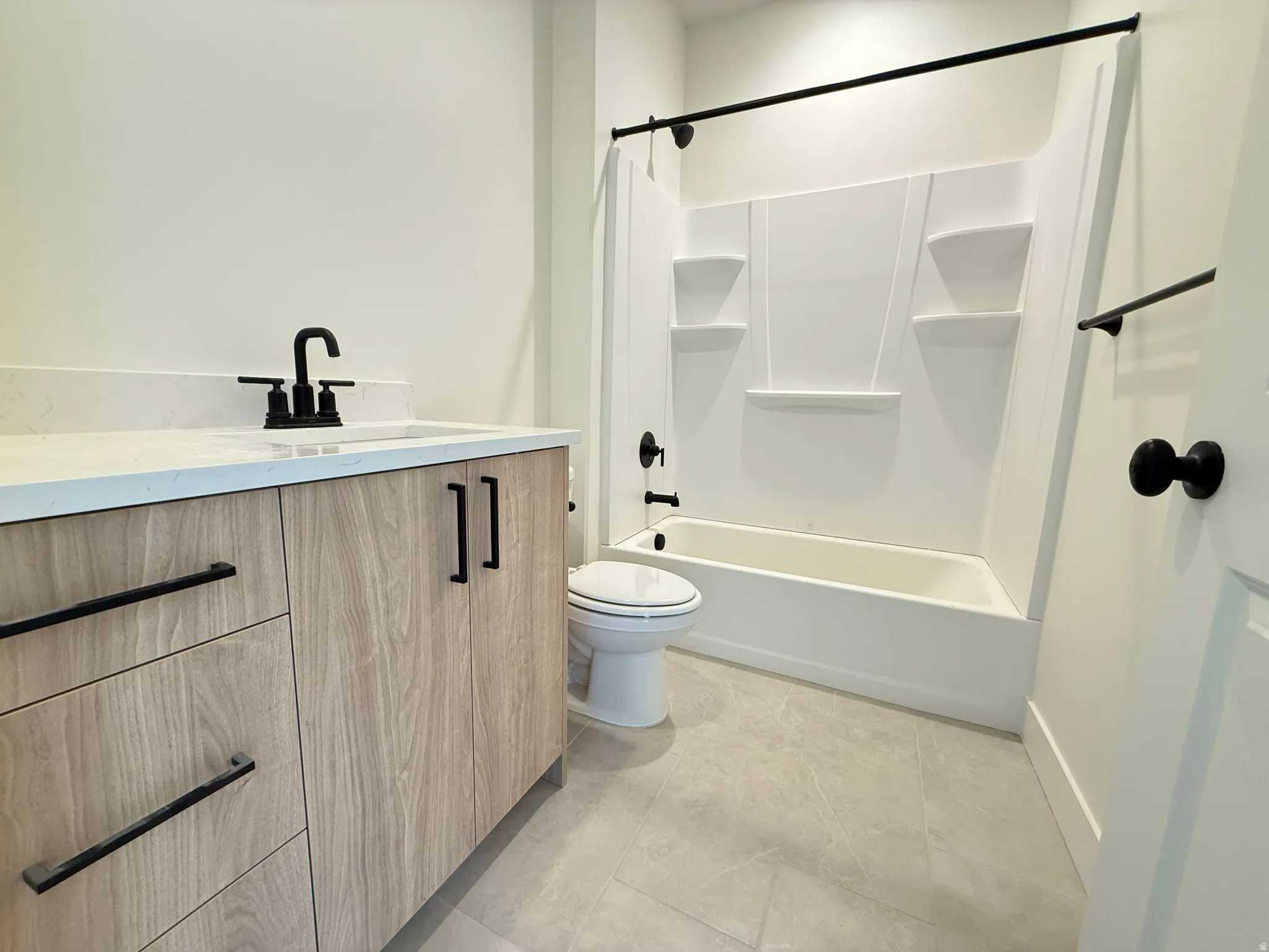 Modern bathroom featuring a wood-finish vanity with matte black hardware, a light-colored countertop, and a white integrated sink