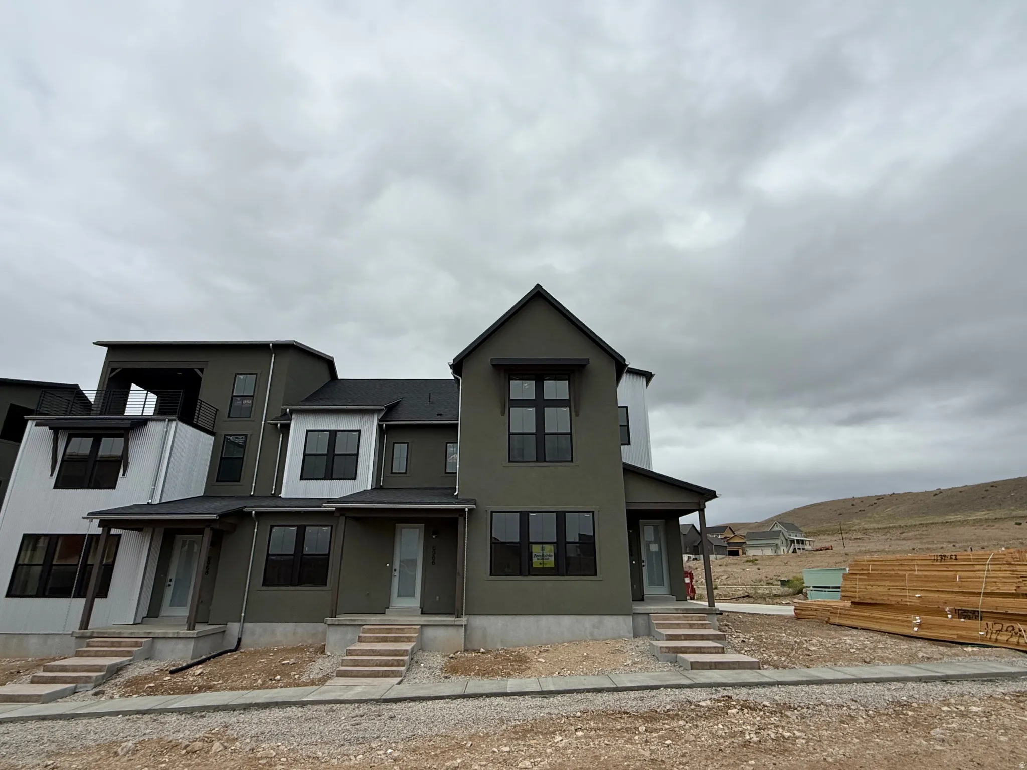 Modern townhome exterior featuring an angular roofline, dark-framed windows, and a covered porch entry